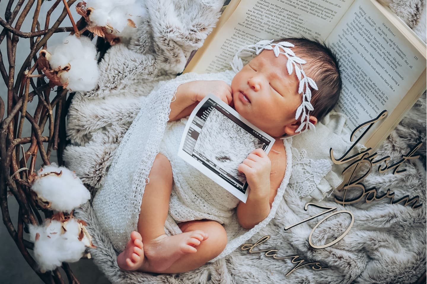 エコー写真を持ち本を枕に眠る新生児
