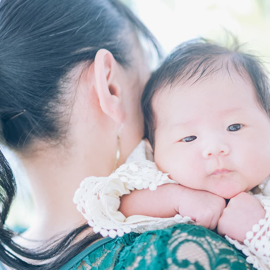 お母さんの肩に顔を乗せる赤ちゃん